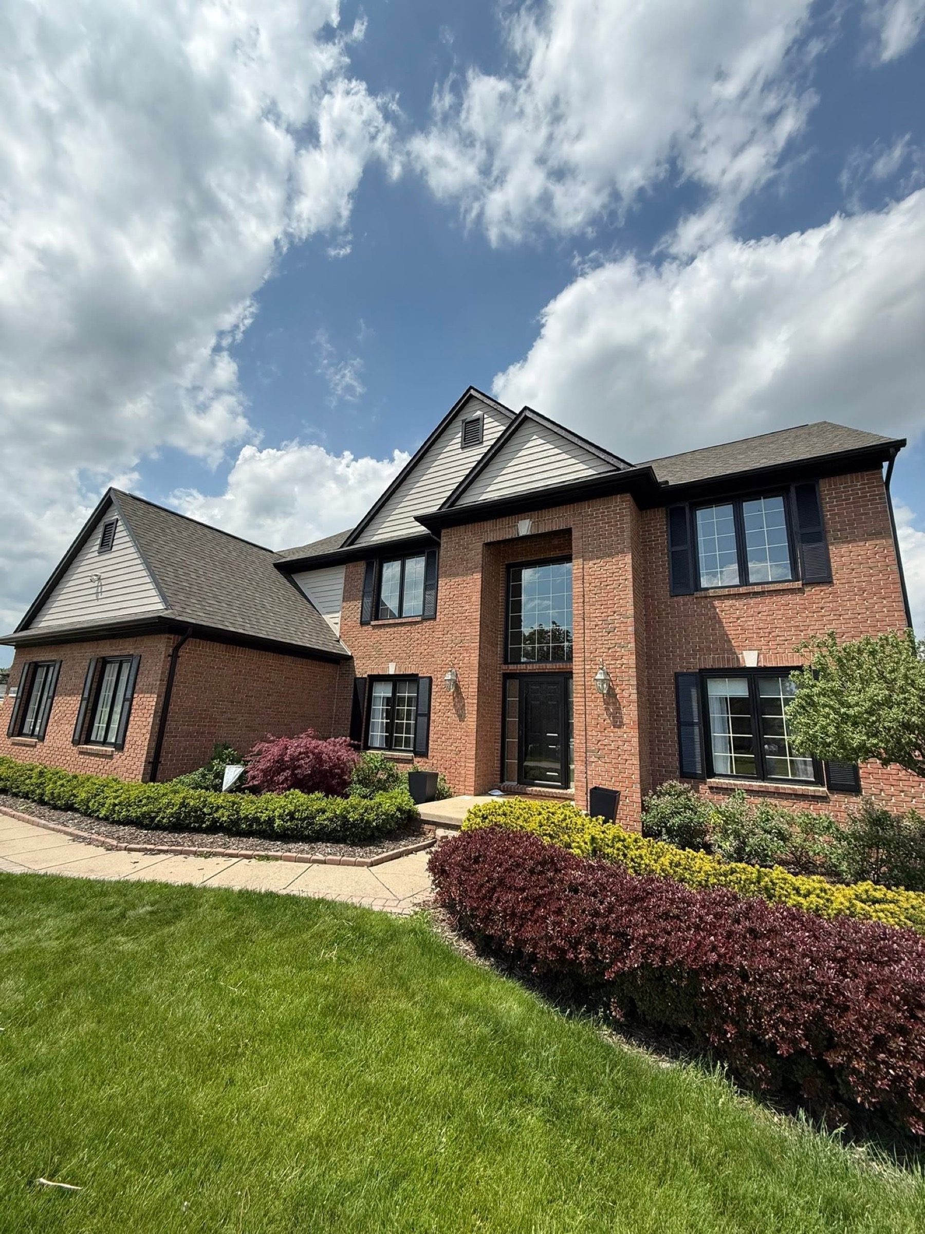 Front exterior of a brick home with dark shutters and painted trim