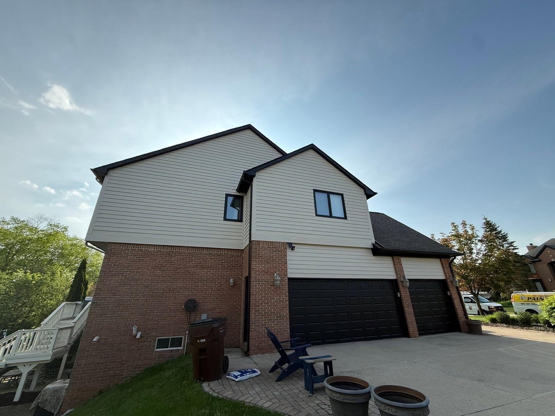 Exterior garage side of a brick home with painted upper siding and dark garage doors
